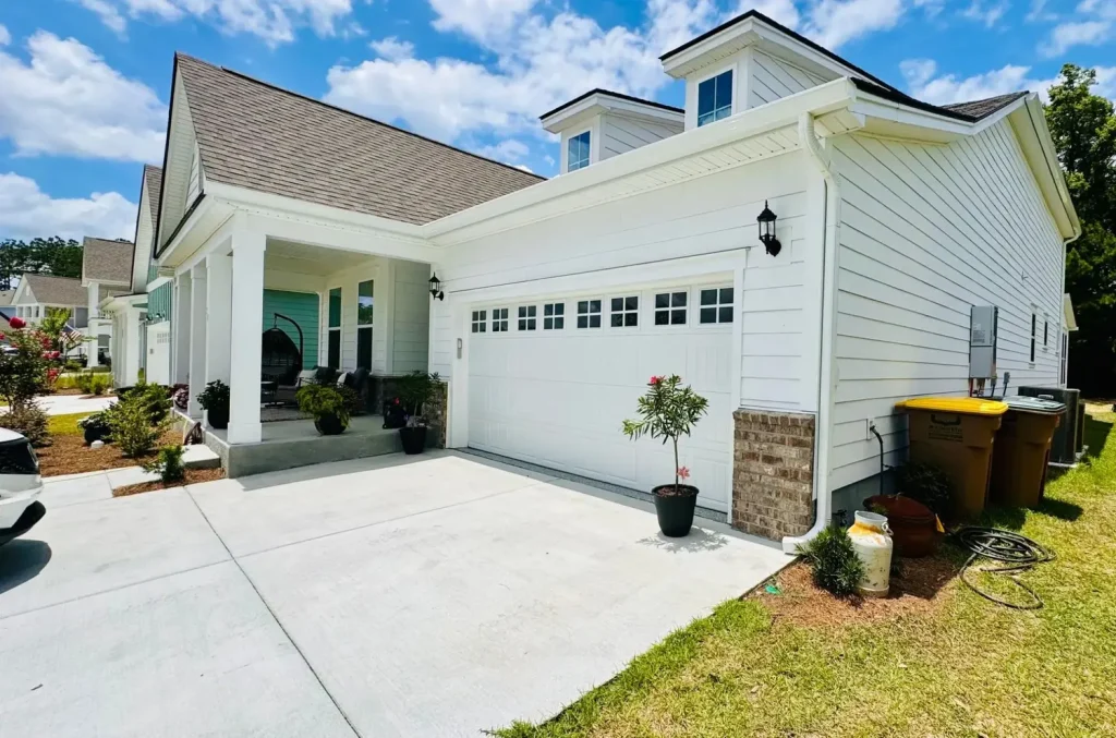 Single-story home with white siding, a shingle roof, white gutters, and a garage, featuring a covered front entry and landscaped driveway.